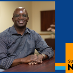 Dan Nyaronga smiles sitting at a table.