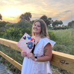 A photo of Samantha Paige holding her graduation cap