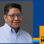 Armando Flores wears glasses and a light blue collared shirt, posing for a headshot against a neutral background.