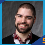 Smiling man with short hair and beard wearing a red plaid shirt and black sweater, next to SUNY Empire 5 Minute Feature logo.