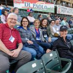 A group of people sitting in a stadium together, smiling for the camera.