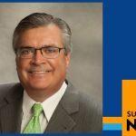 SUNY Empire News graphic frame with photo of a man in a gray suit and green tie wearing glasses smiling against a gray background.