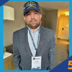 Man wearing a U.S. Navy Submarine Veteran cap and a suit jacket with a conference badge that reads 'Thomas,' next to SUNY Empire 5 Minute Feature logo.