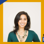 Graphic with a gold background featuring a portrait of Noor Syed smiling with dark shoulder-length hair wearing a green top and layered necklace. A blue shield logo appears in the top left, and the words “Deep Dive” appear in the bottom right.