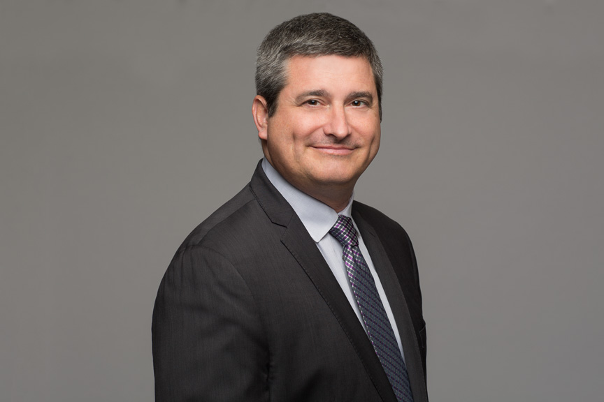 Photo of a man in suit against a gray background.