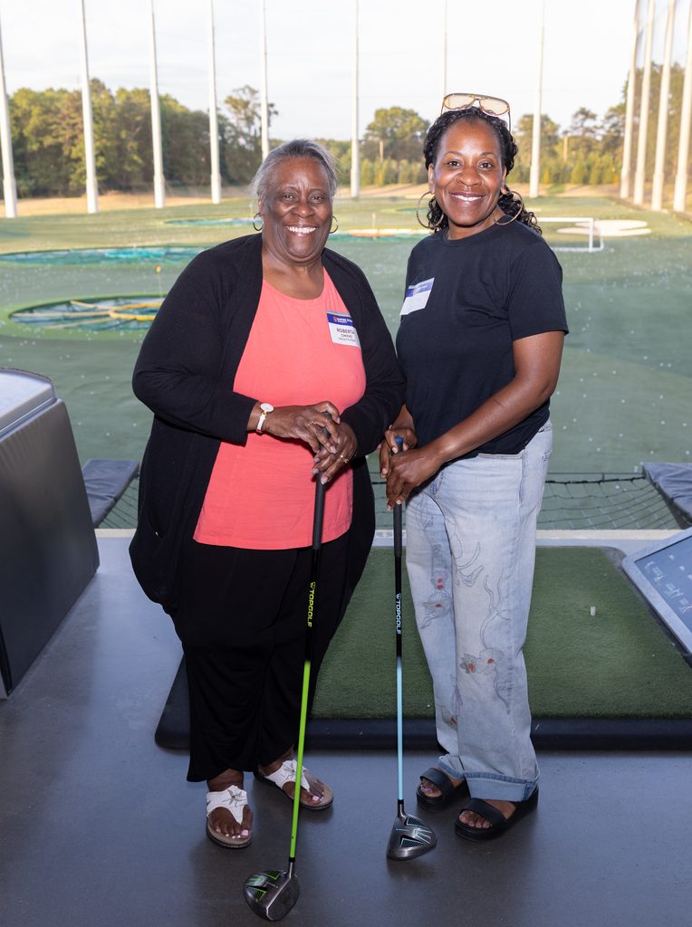 two women holding golf clubs